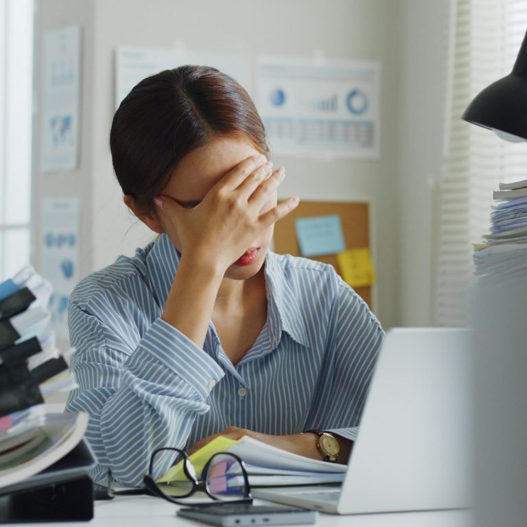 Erschöpfte Frau stützt ihren Kopf auf die Hand.